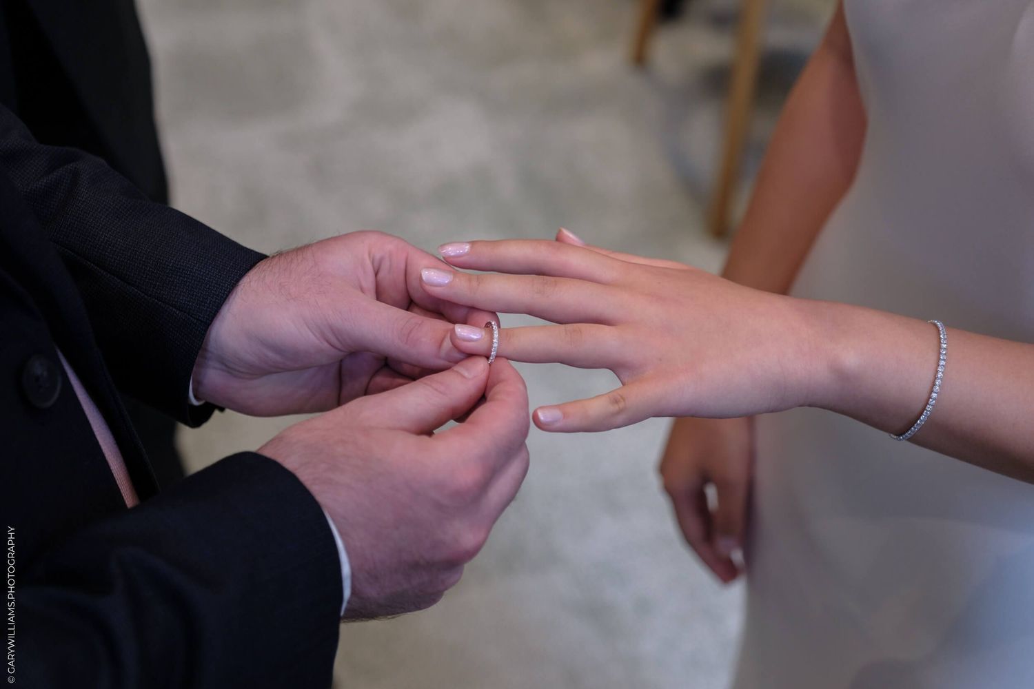 Close-up shot of hands exchanging wedding ring during marriage ceremony.