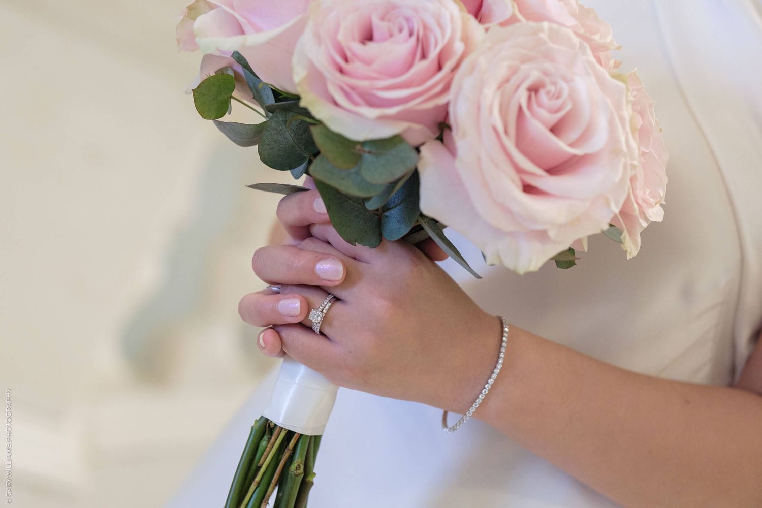 A delicate bouquet of pink roses held by hands adorned with a silver bracelet.