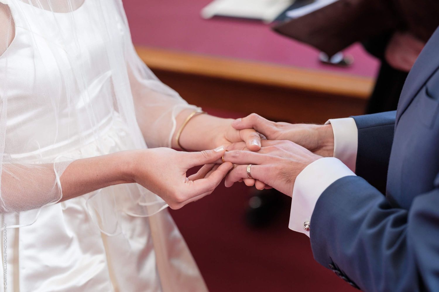 Close-up view of hands exchanging rings during a traditional wedding ceremony.