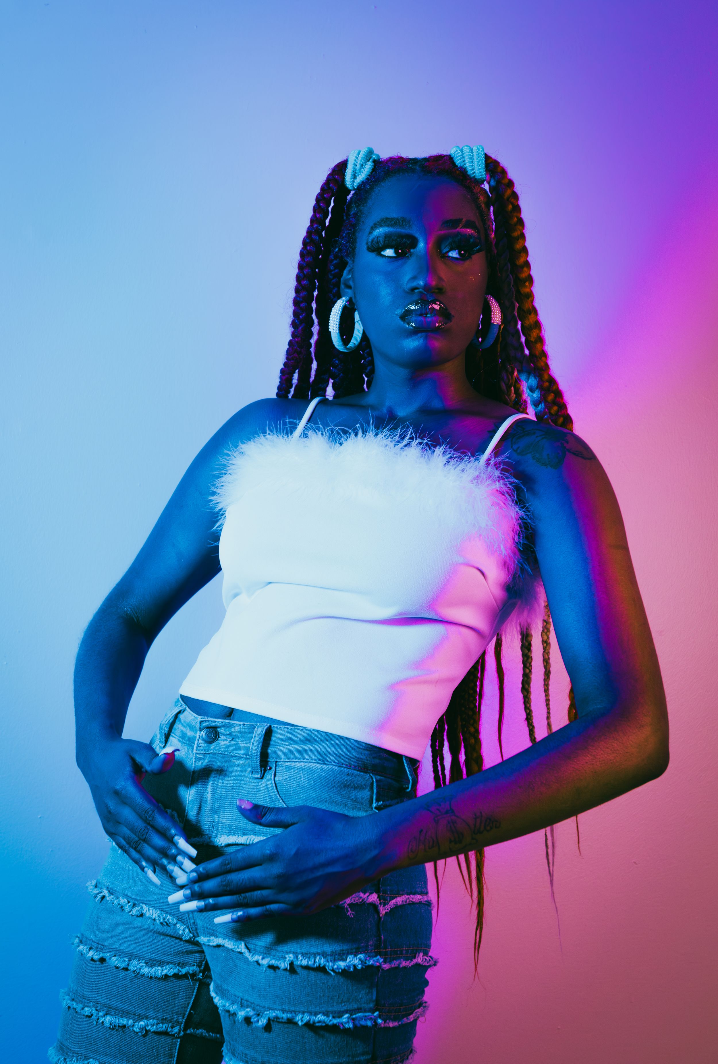 Stylish fashion portraits with neon lighting and denim against colorful gradient background.