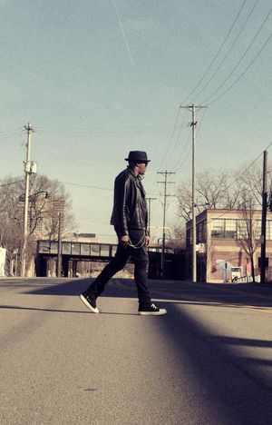 Figure in dark clothing performing smooth moonwalk moves on empty street.