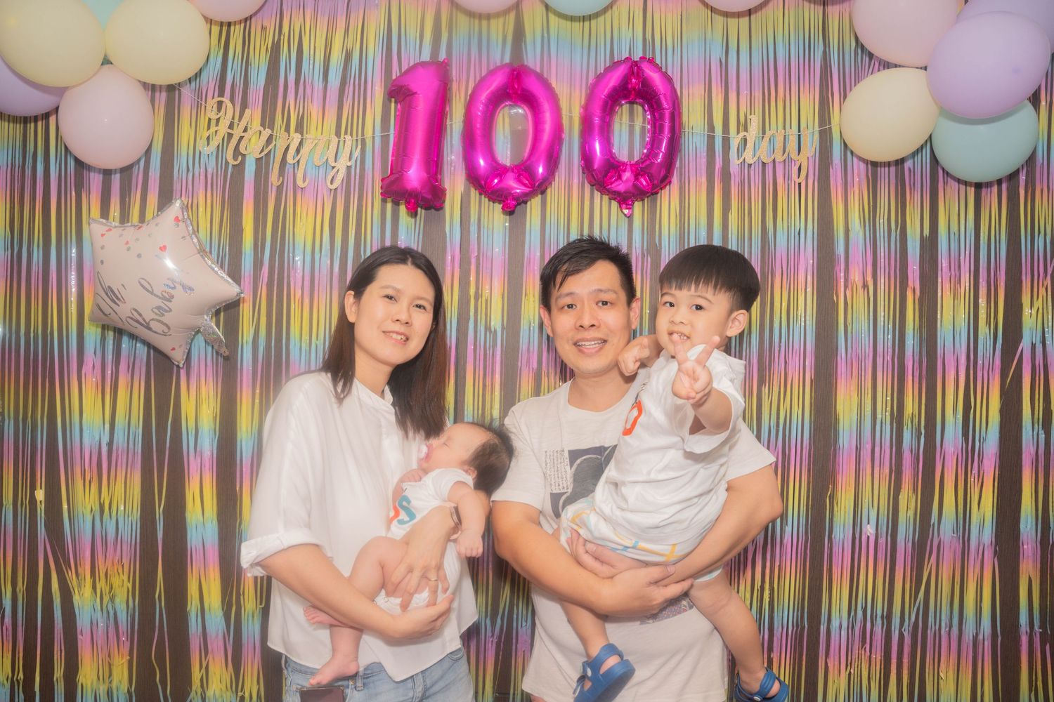 Birthday celebration setup with colorful streamers and balloons against a wall for a 100th birthday party.