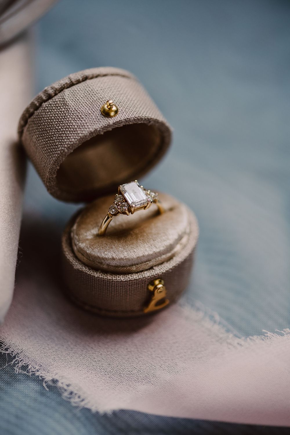 Close-up view of an elegant diamond engagement ring in a beige velvet ring box.