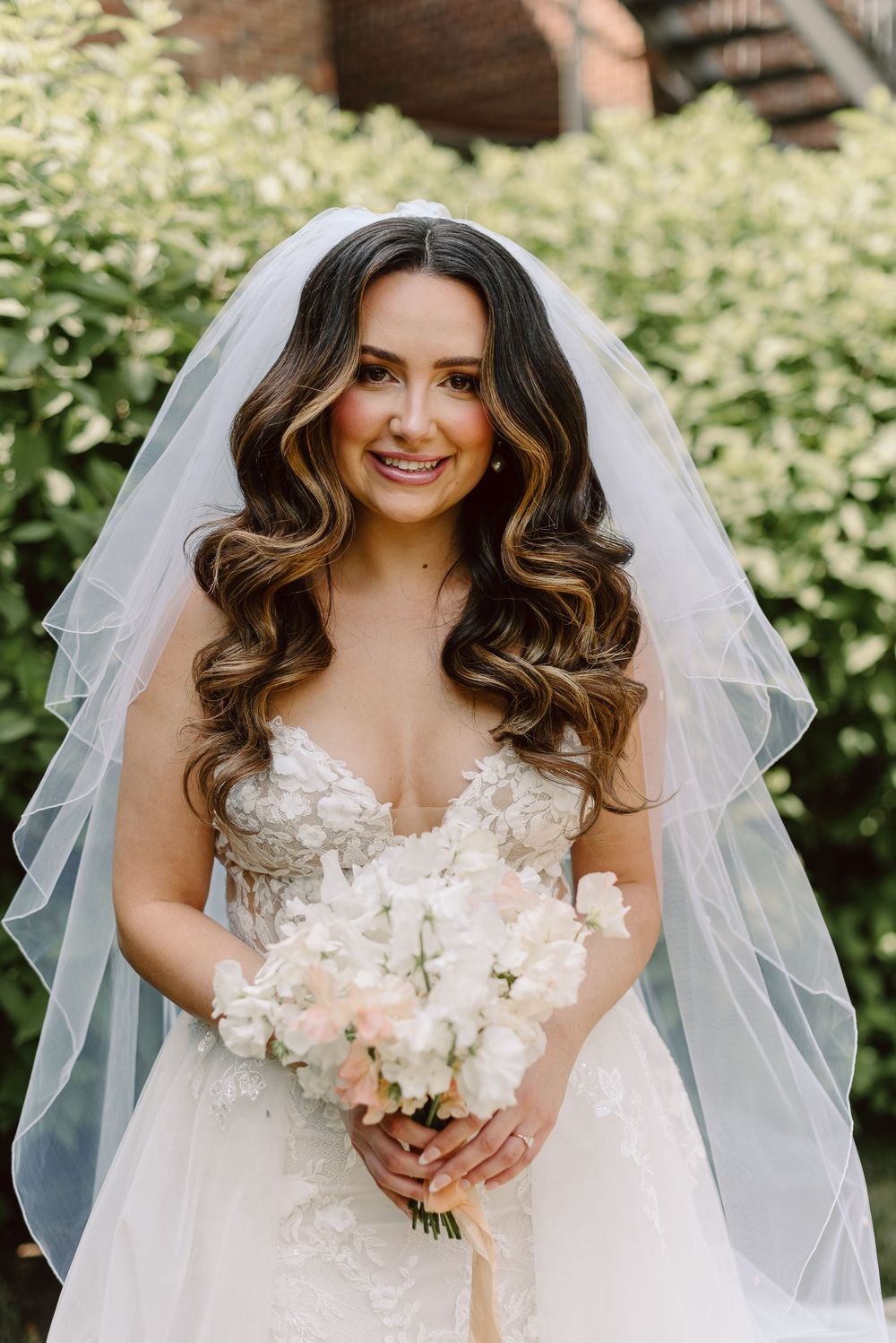 Wedding attire with intricate floral details and flowing veil in a garden setting.