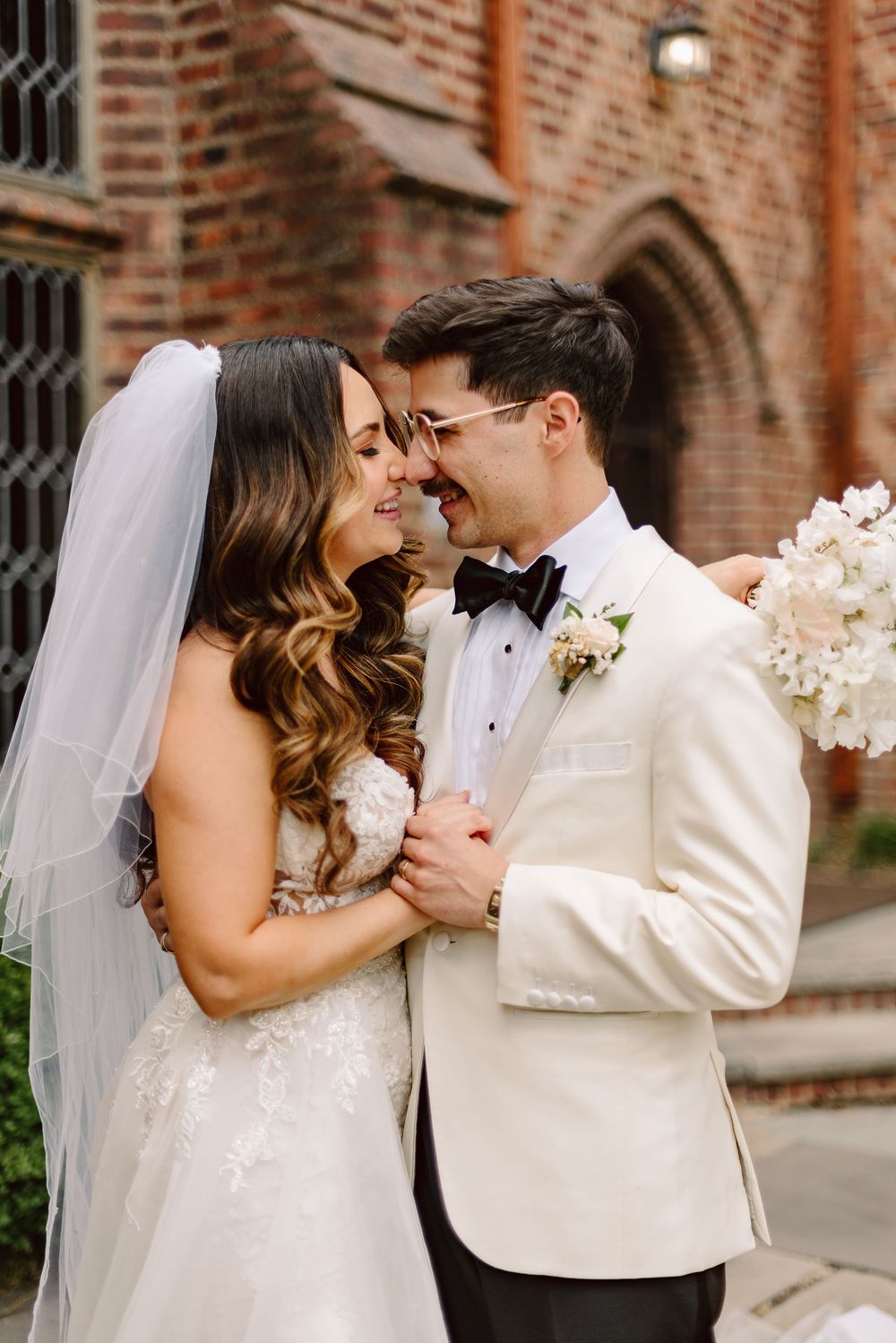 A romantic series of wedding photos shows a couple embracing against a brick wall backdrop in classic white attire.