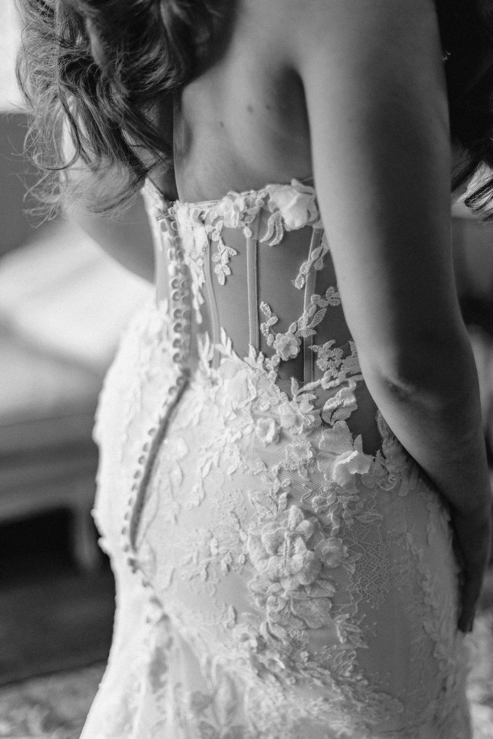 Close up detail of intricate lace applique on back of white wedding dress.