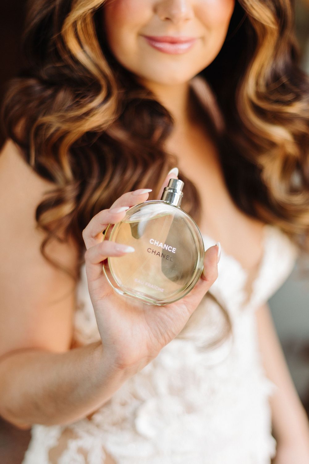 A perfume bottle is held up against a soft background.