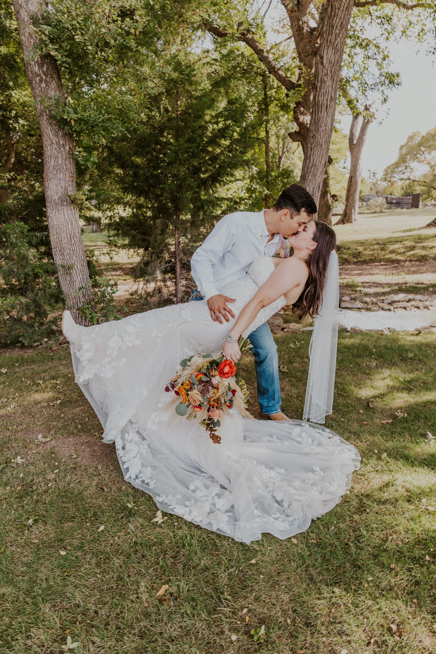 Newly weds share a dip kiss in the trees.