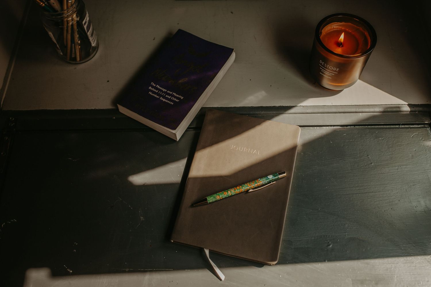 A wooden pen holder organizer sits on a dark desk with various writing instruments and office supplies.