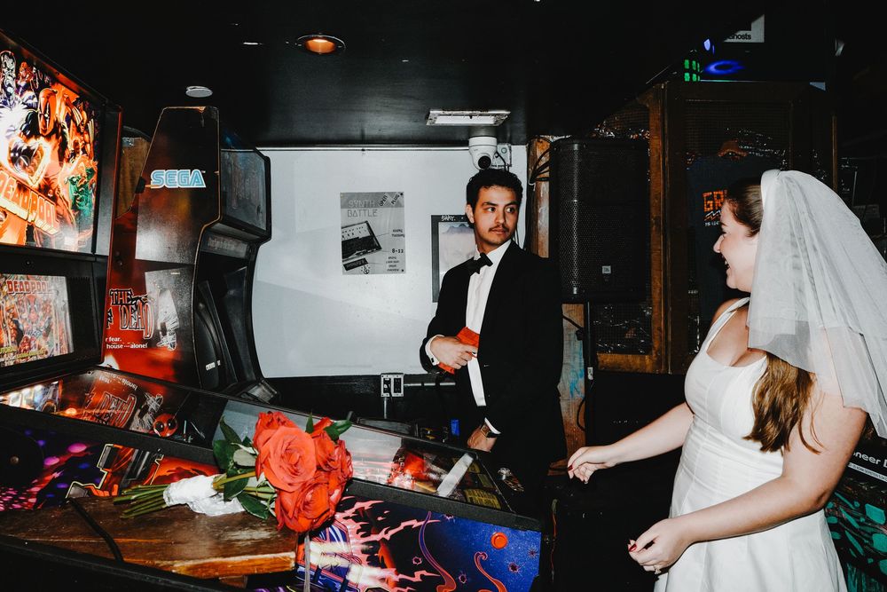 People celebrate at a wedding reception party on the dance floor under dim lighting at night.