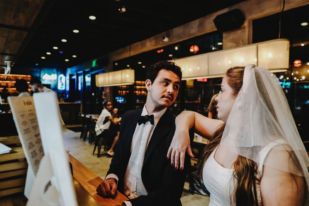 Dance floor filled with joyful wedding party guests in formal attire having fun at an indoor reception venue.