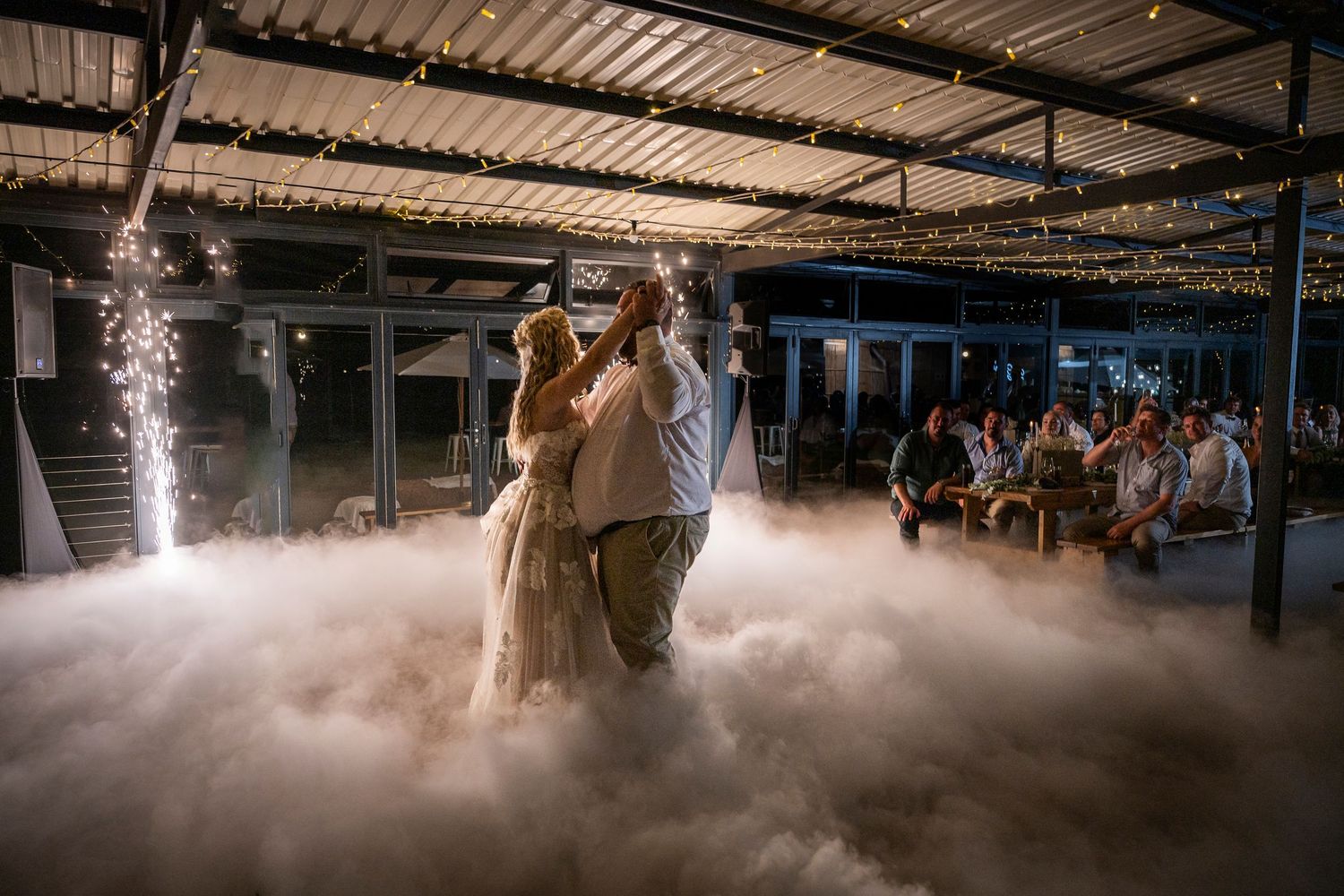 A couple dances their first dance at a rustic warehouse wedding venue with dramatic fog effect on the dance floor.