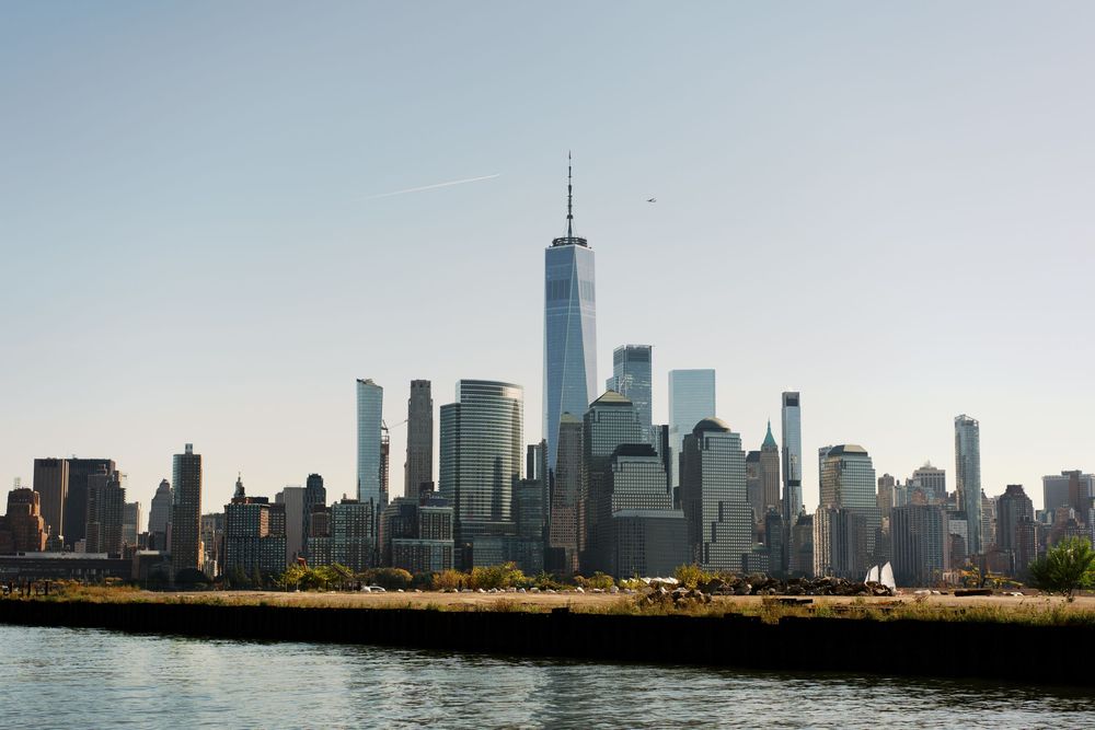 Lower Manhattan skyline view across the water featuring One World Trade Center.