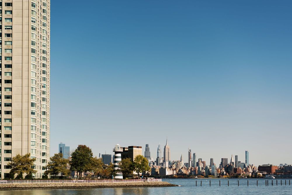 Modern residential tower overlooks skyline and waterfront on a bright sunny day.