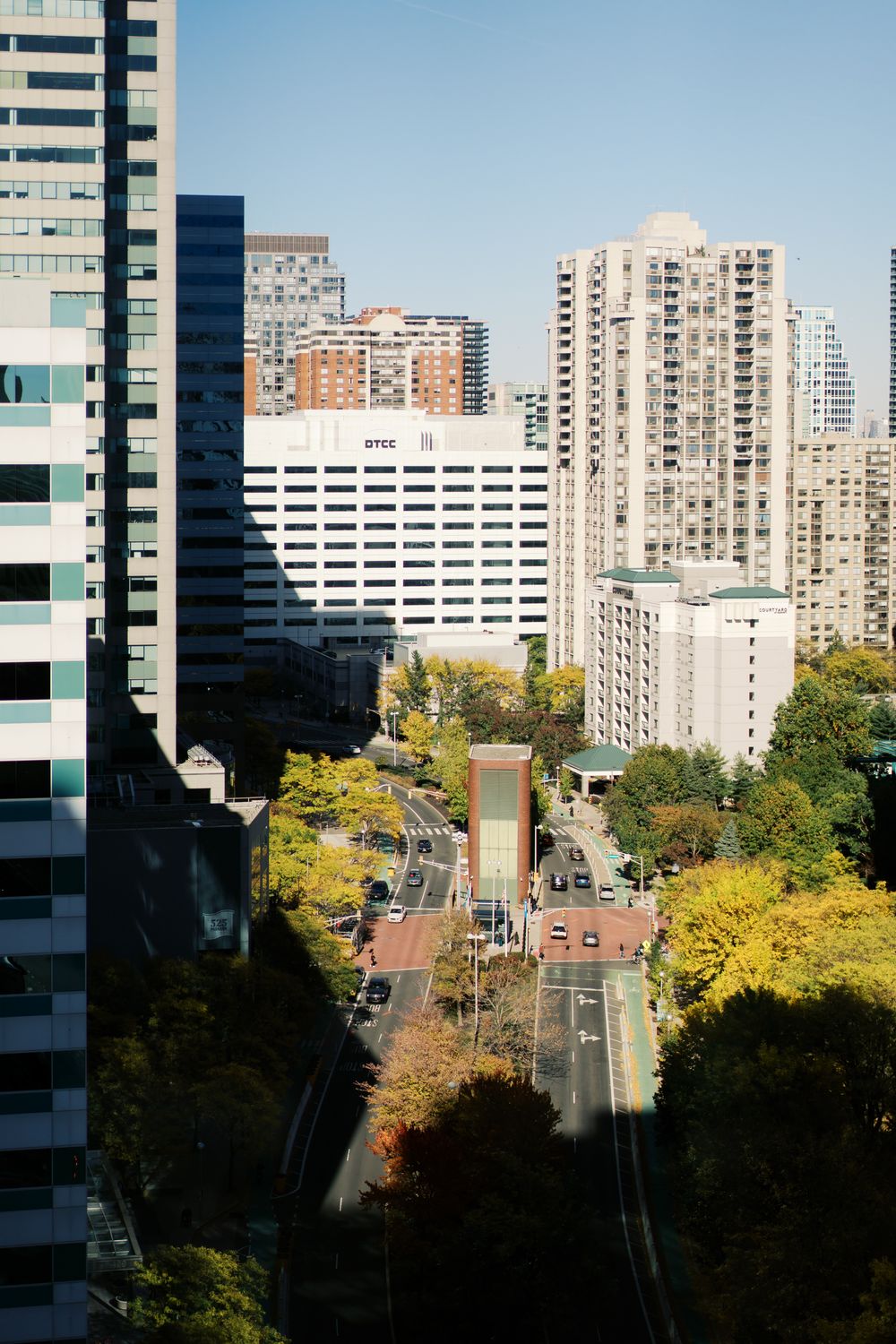 Modern urban cityscape with tall buildings and autumn trees viewed from high angle.