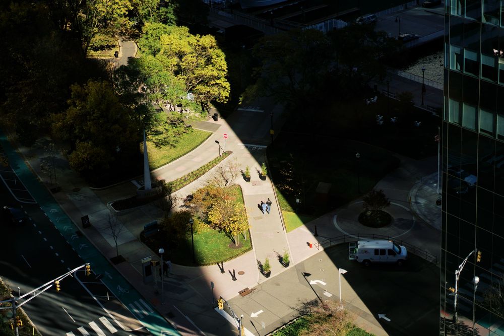Aerial view of urban landscaping and walkways between modern buildings in late afternoon shadows.