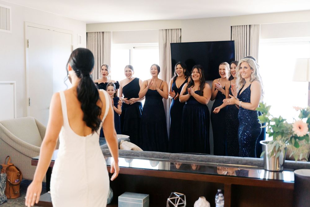Group of elegantly dressed people gathered in a bright indoor event space with mirrored walls.