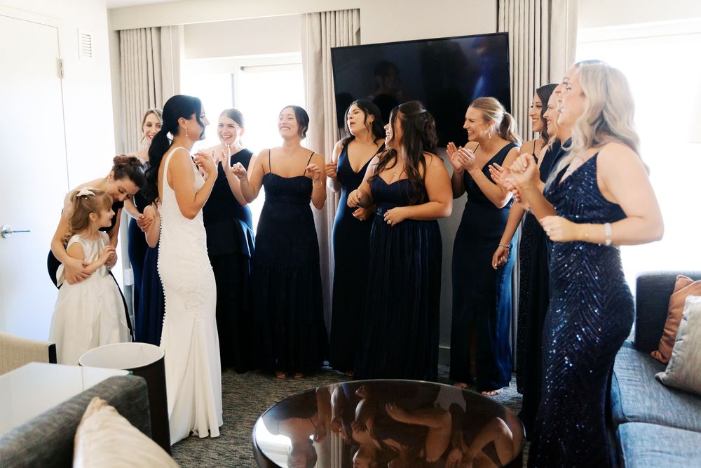 People in formal attire celebrating during an indoor event with light streaming through windows.