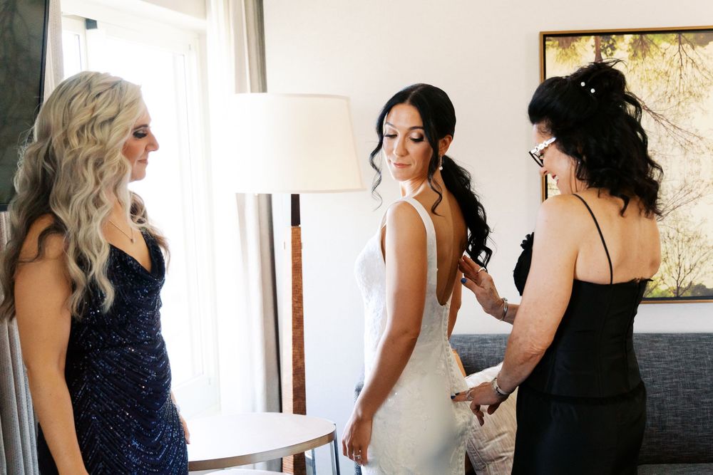 A group gets ready in an elegant room with bridesmaids and bridal party preparing in white and navy dresses.