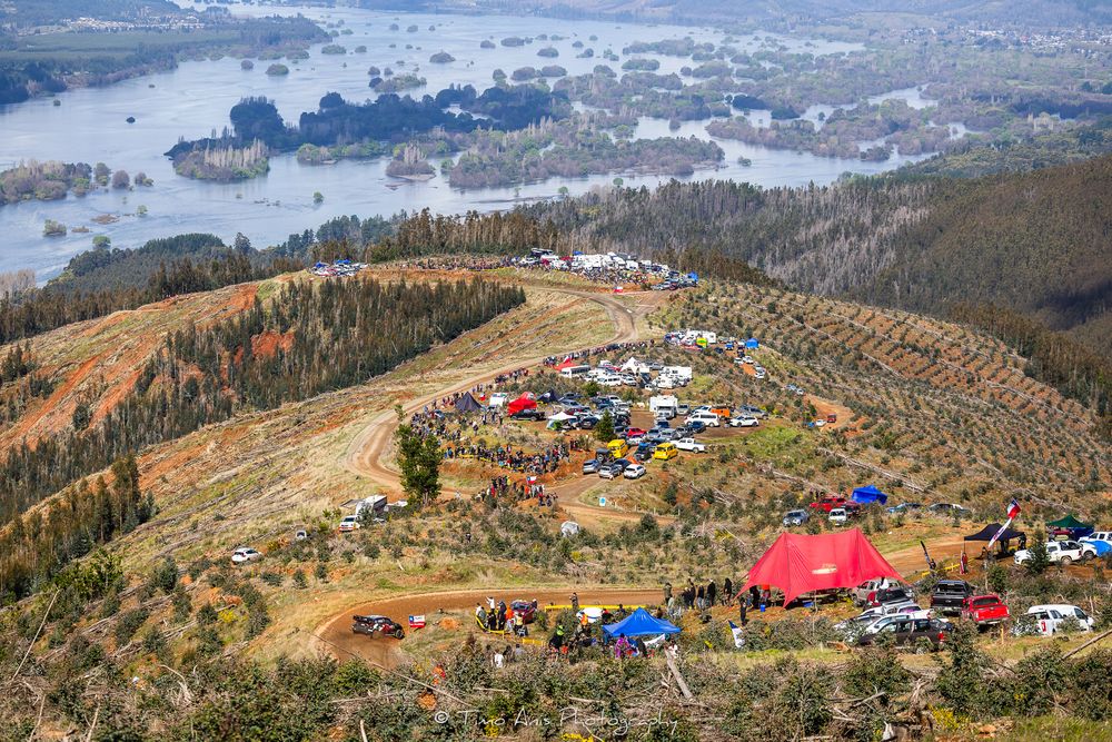 Panoramic view of colorful tents scattered across mountain ridges during autumn with forest landscapes in the distance.