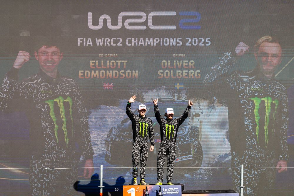 Large monitors at rally event show racing telemetry and colorful graphics during WRC2 championship display.