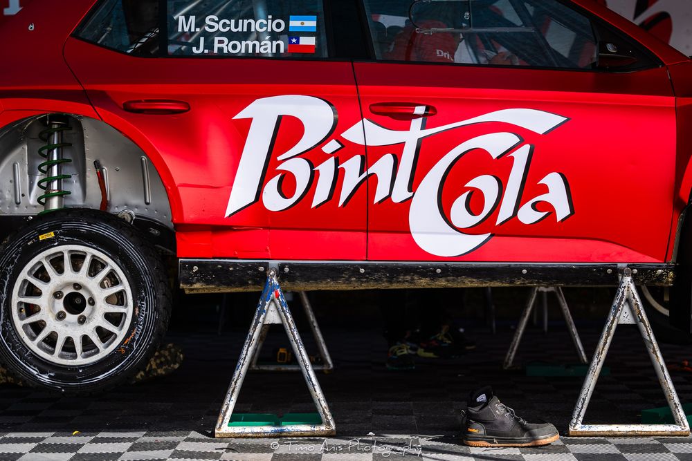 Several red Coca-Cola branded vehicles and merchandising displays parked in line at an event or exhibition.