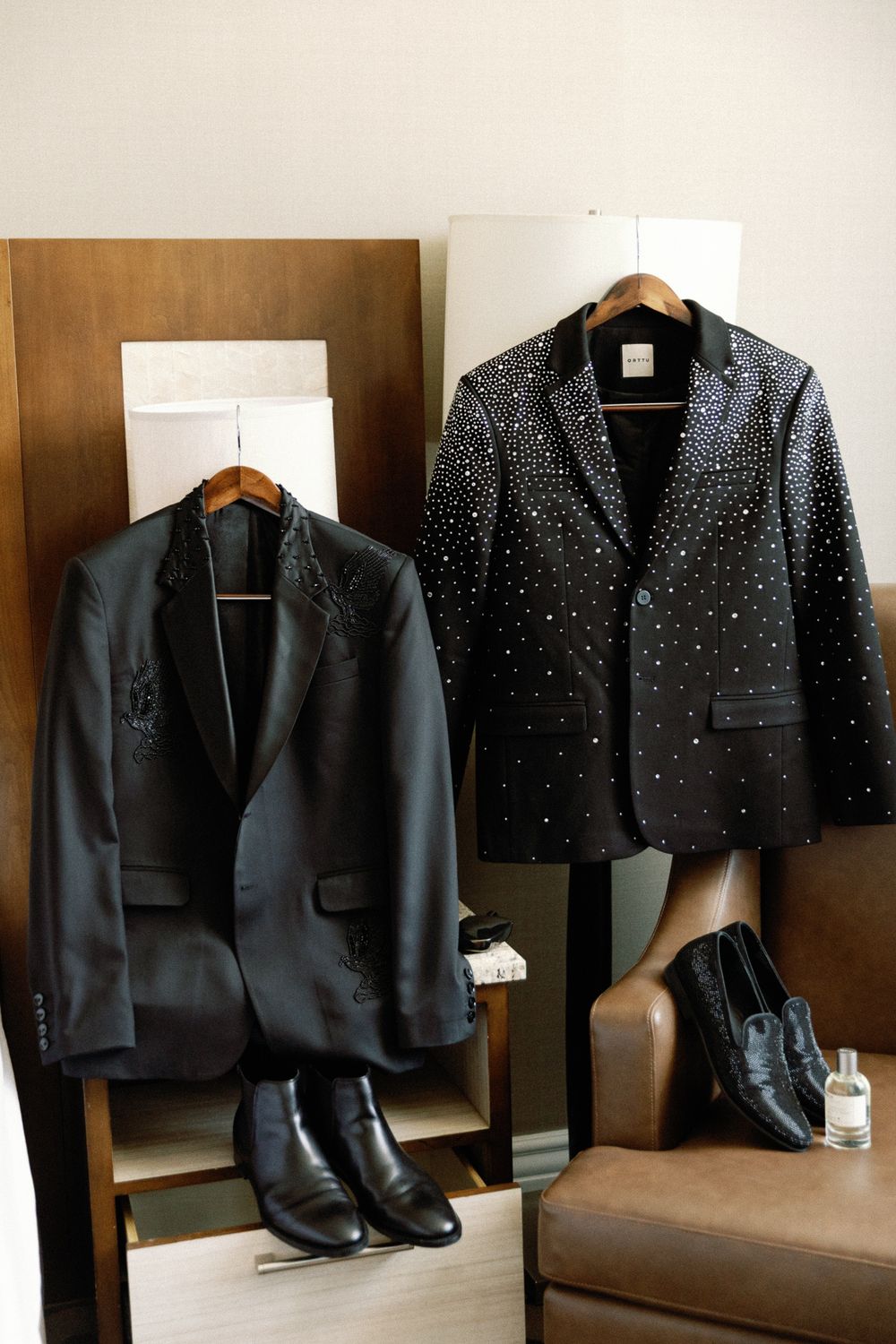 Two embellished black tuxedo jackets displayed with dress shoes for a wedding.