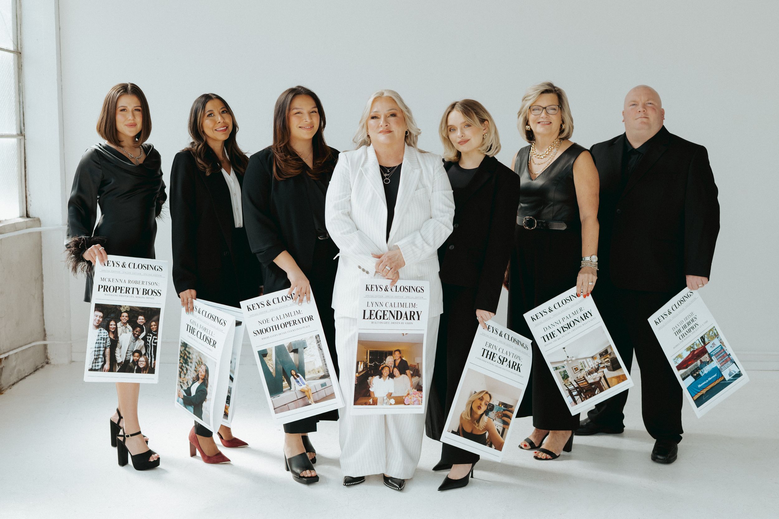 Group photo of real estate team in black and white outfits against light background.