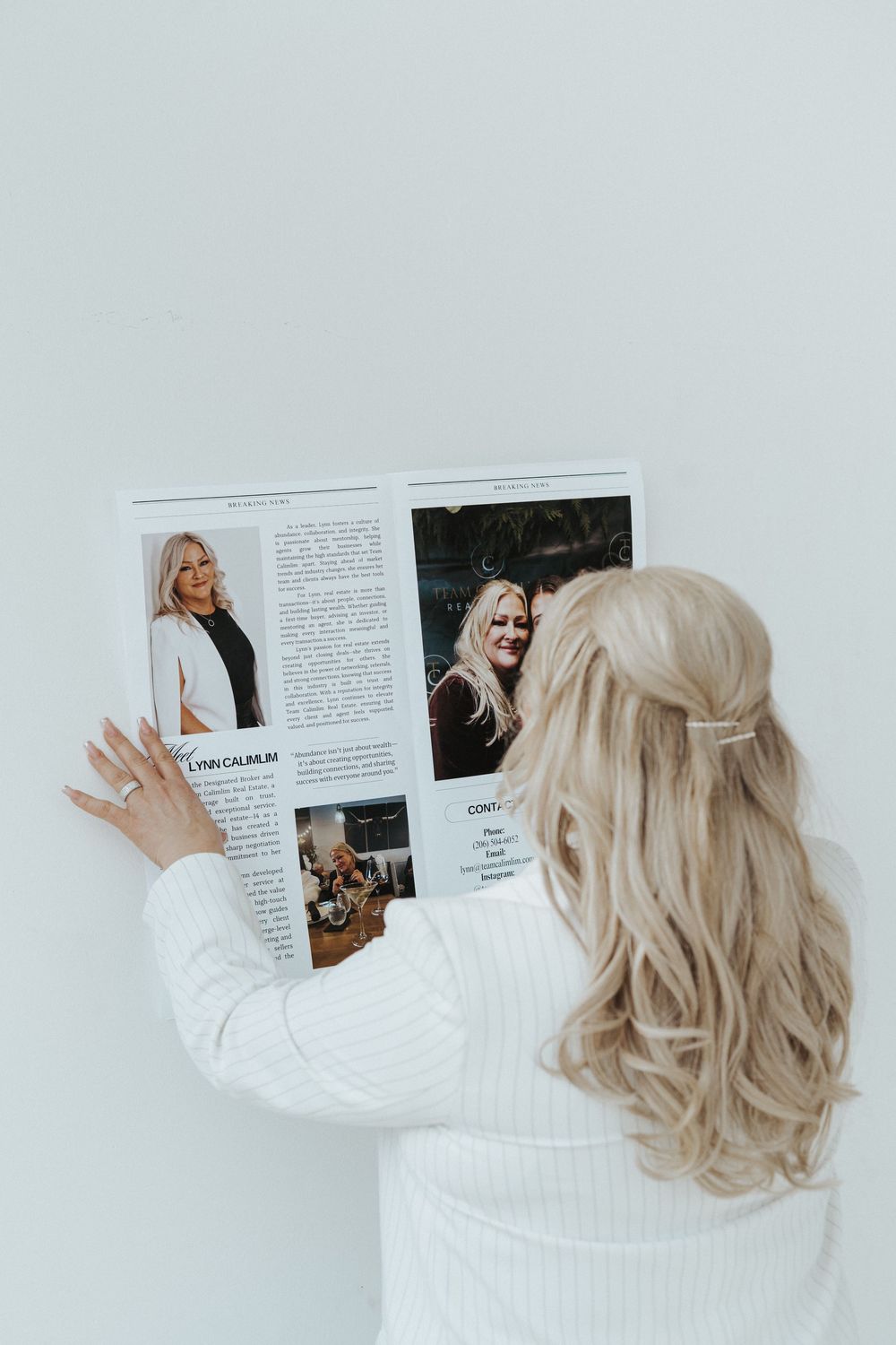 Woman in white sweater reading a professional magazine against light background.