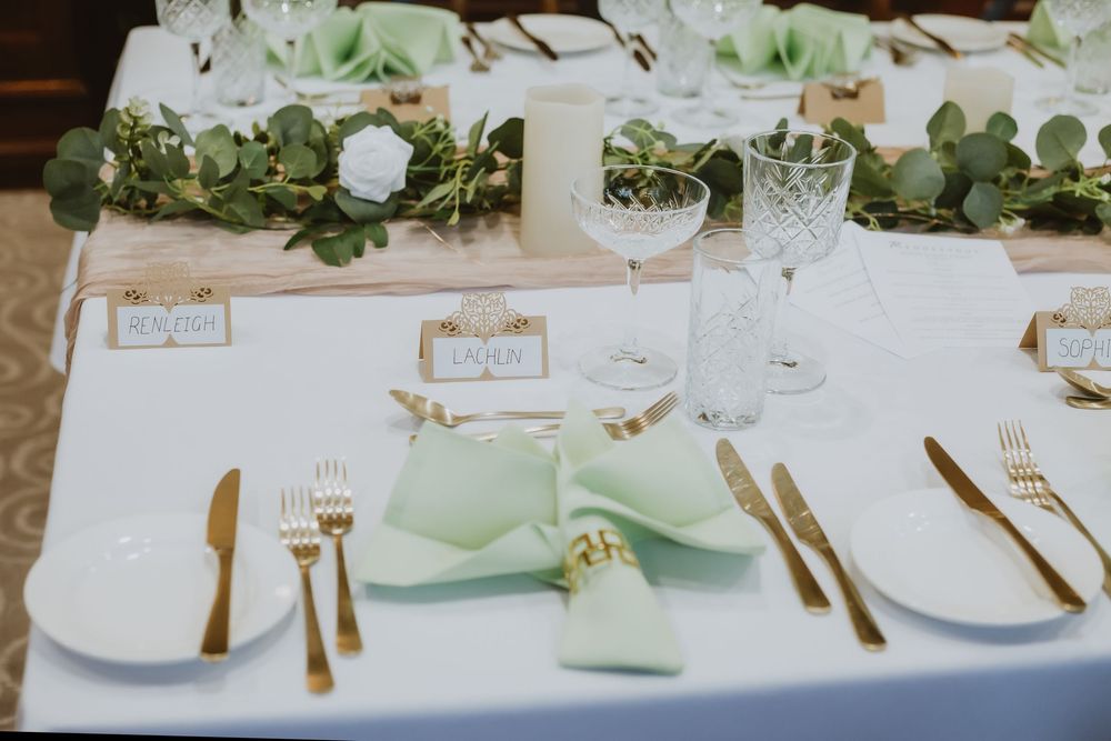 Elegant wedding table settings with mint green napkins, gold cutlery, and delicate floral accents on white tablecloths.