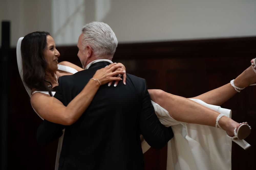 A couple dancing together at an indoor wedding reception in an elegant ballroom setting.