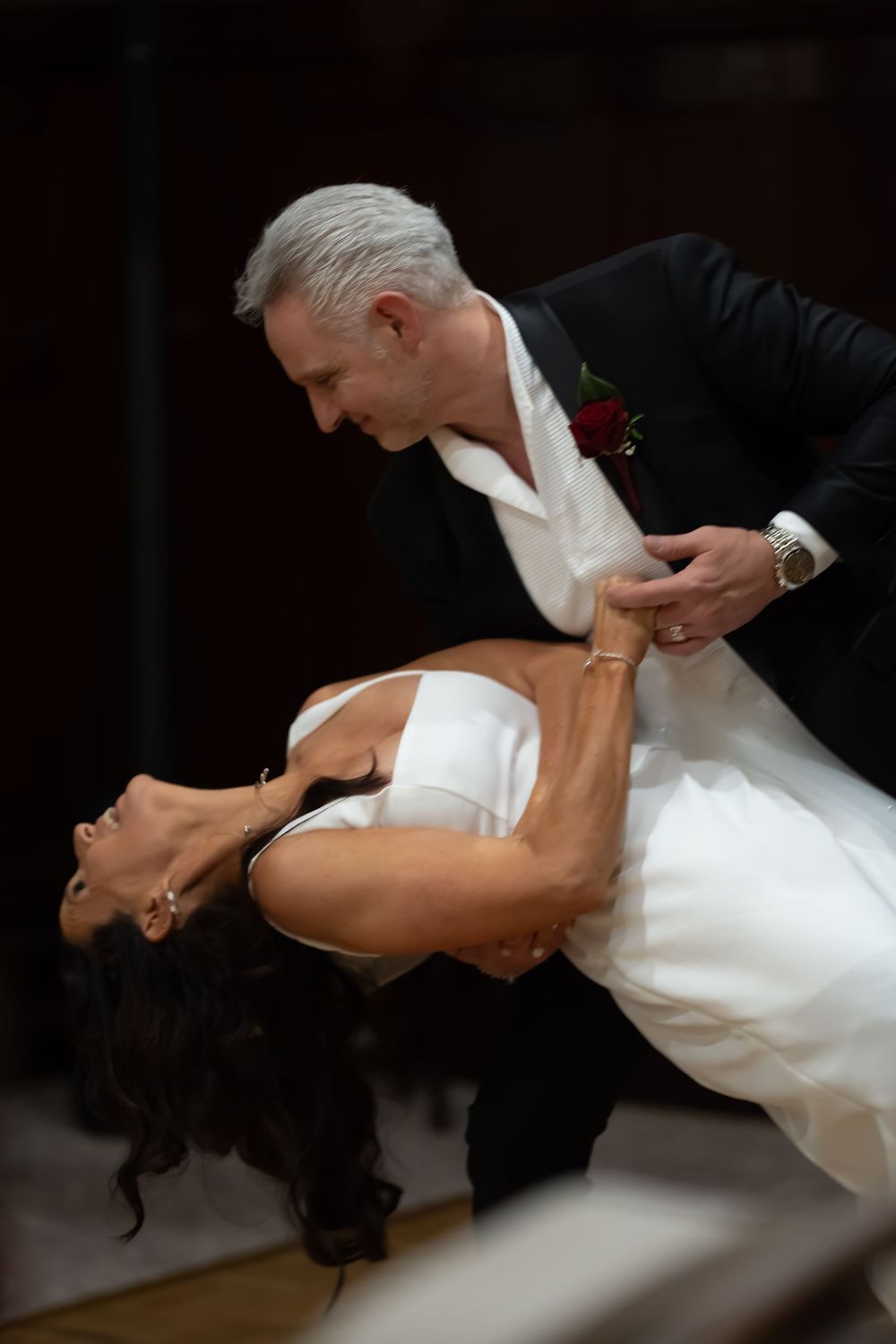 A dance couple performs a dramatic dip move during a ballroom performance in elegant black and white attire.