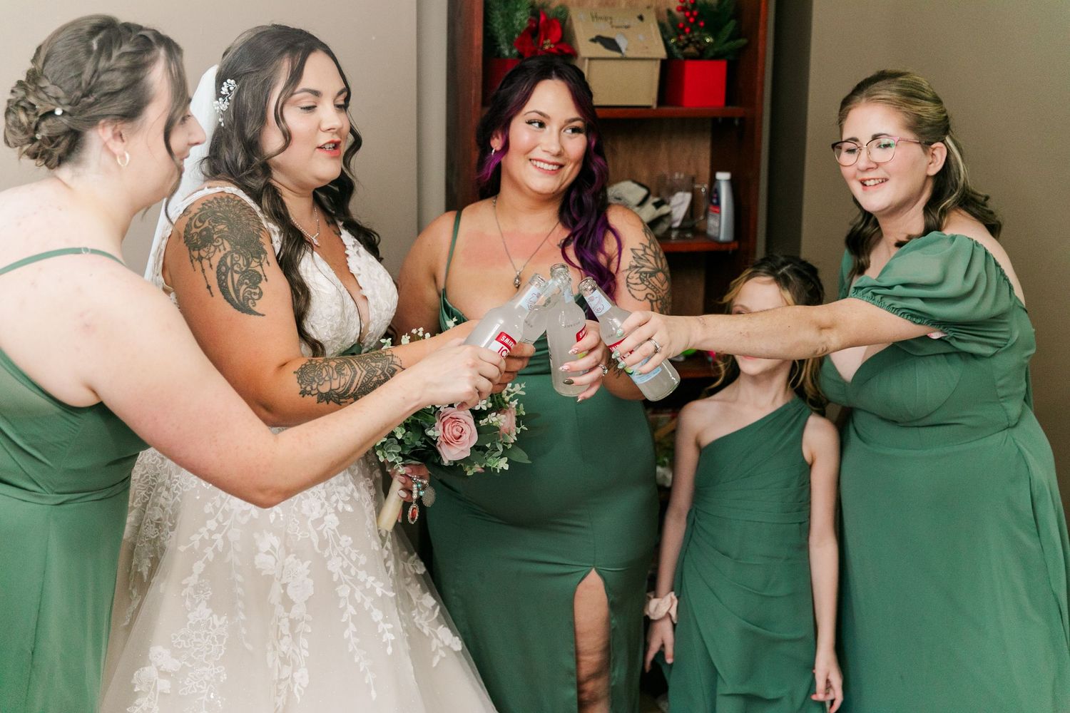 A group in white and emerald green dresses toasting with beverages during a formal celebration.