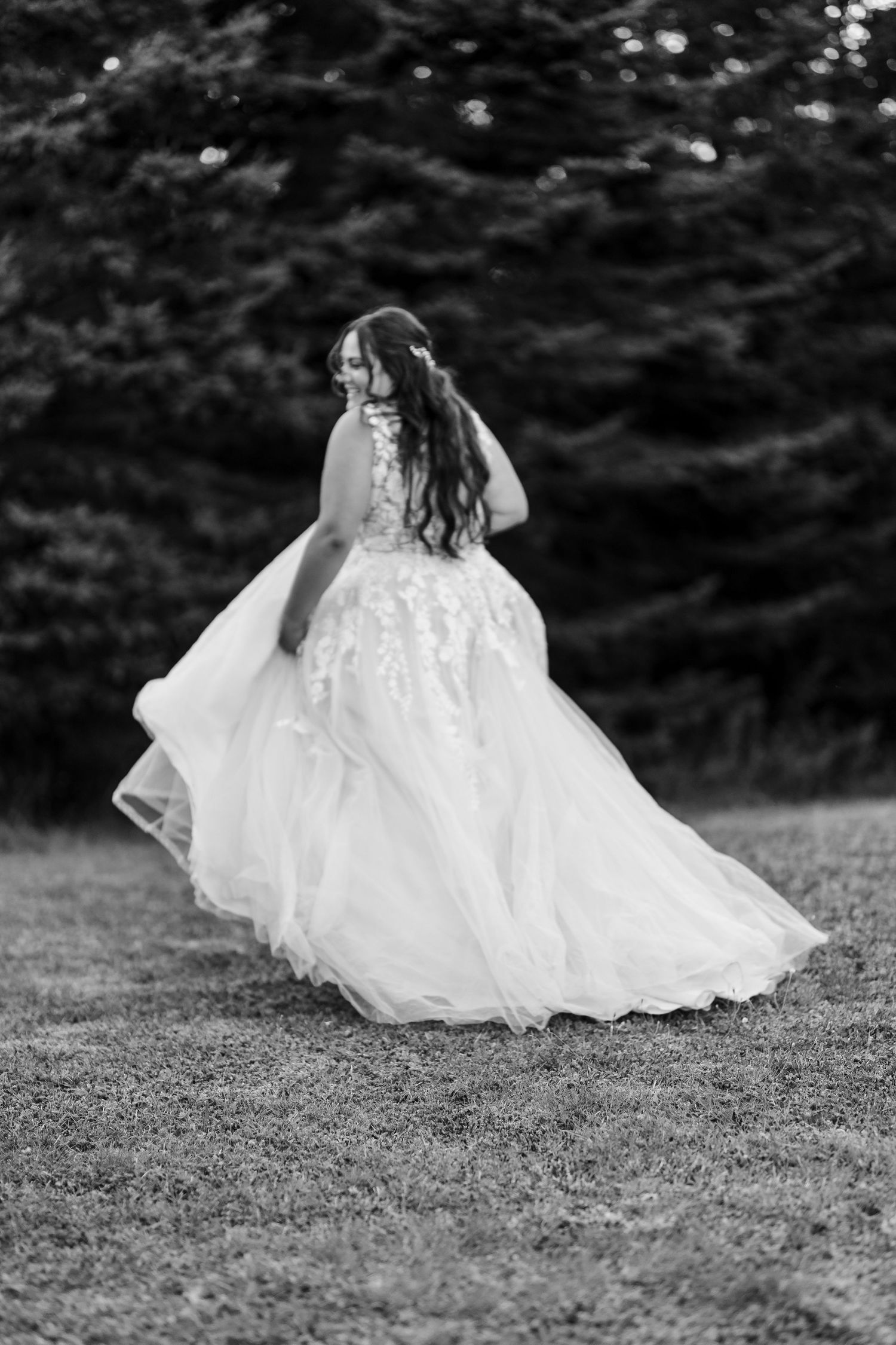 Black and white artistic sequence of a white dress flowing in motion across grass in an ethereal wedding photo series.