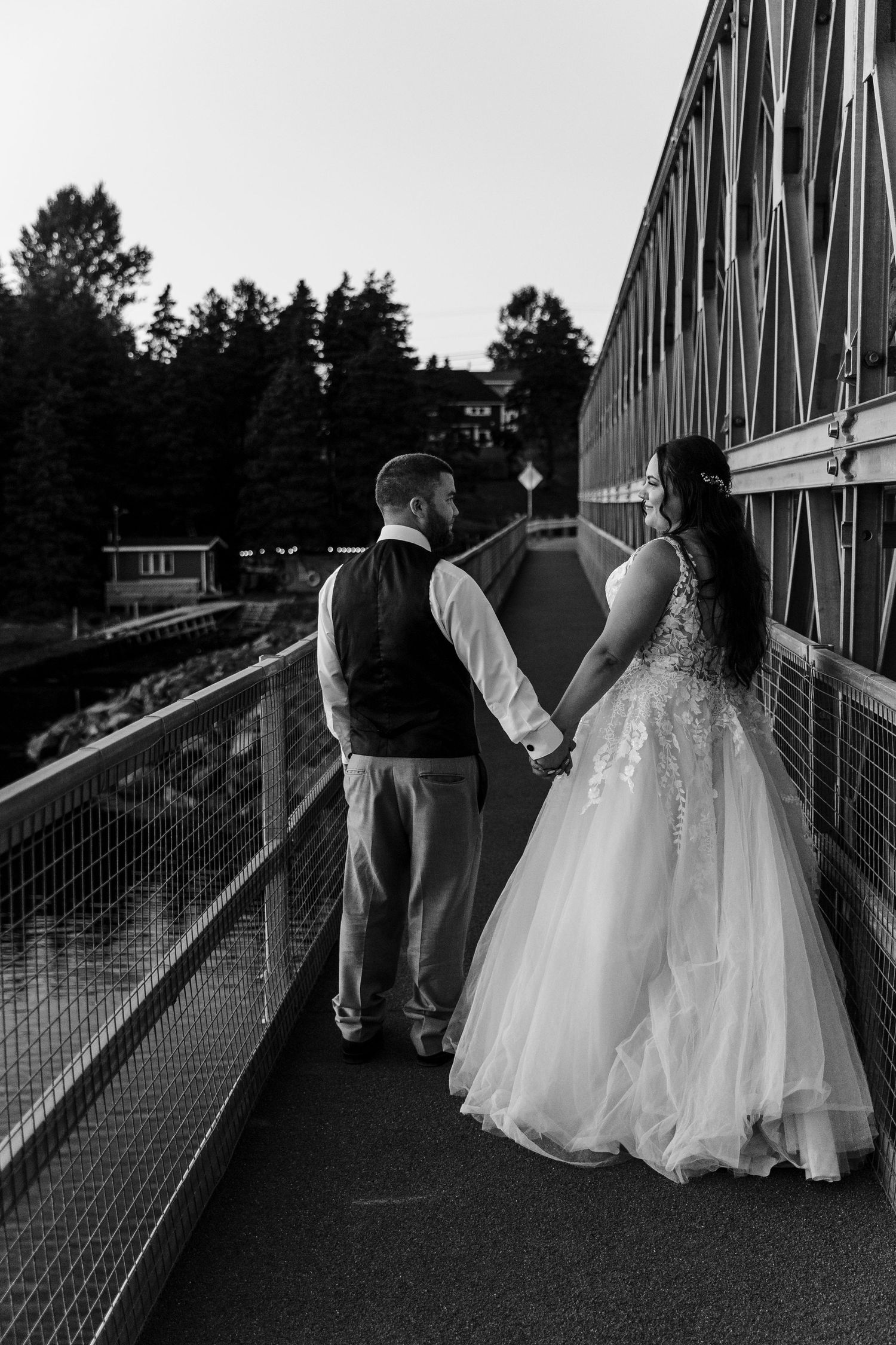 A collection of wedding photos showing a couple walking along a metal bridge in black and white photography.