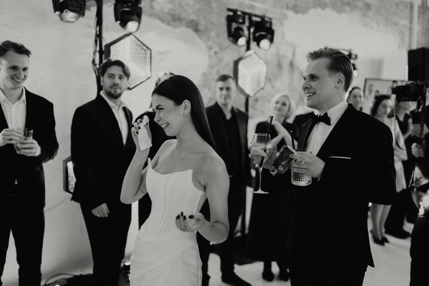 Wedding party celebrating in a historic venue with arched windows and stone walls.