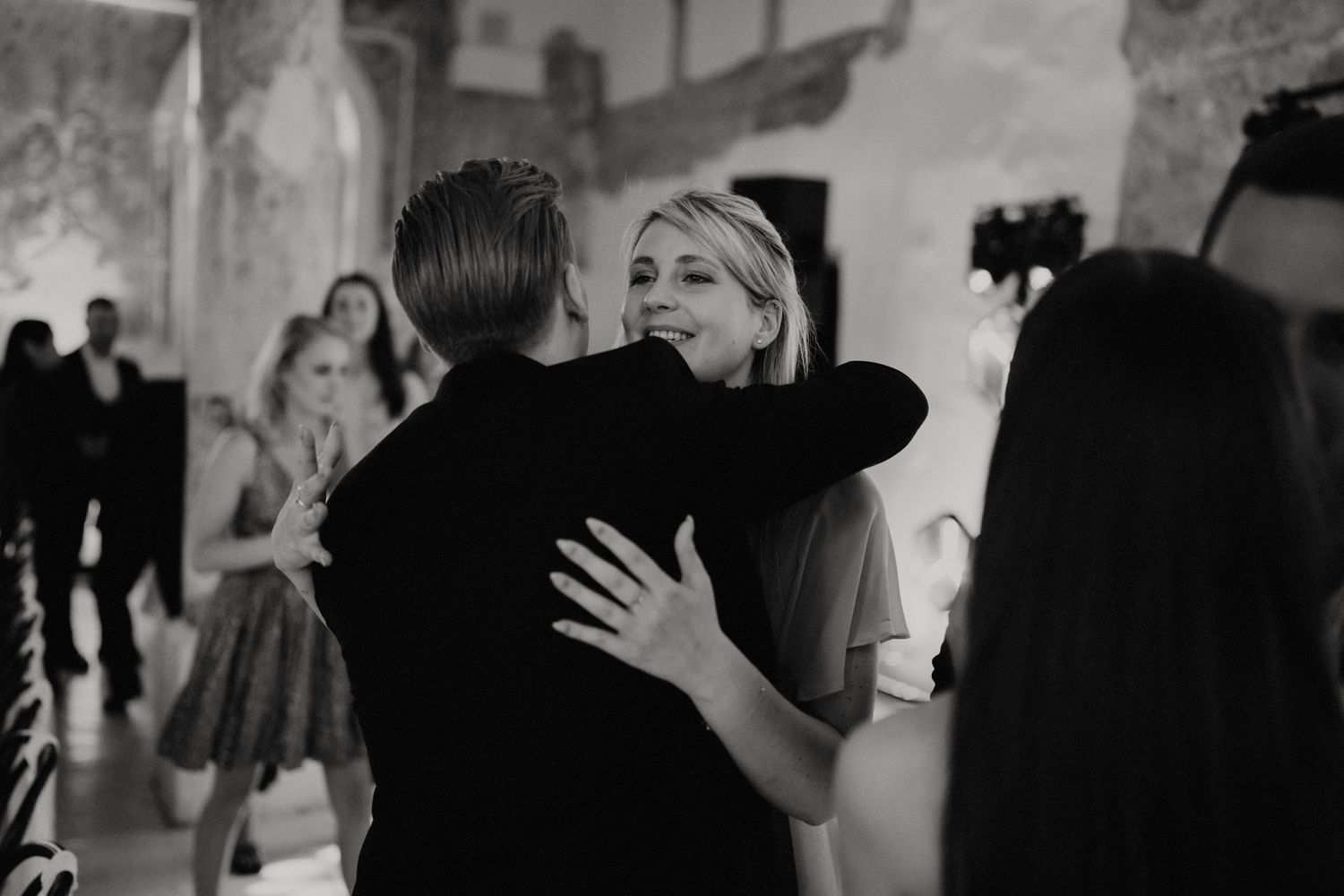 Black and white candid shots of wedding guests celebrating at a reception.