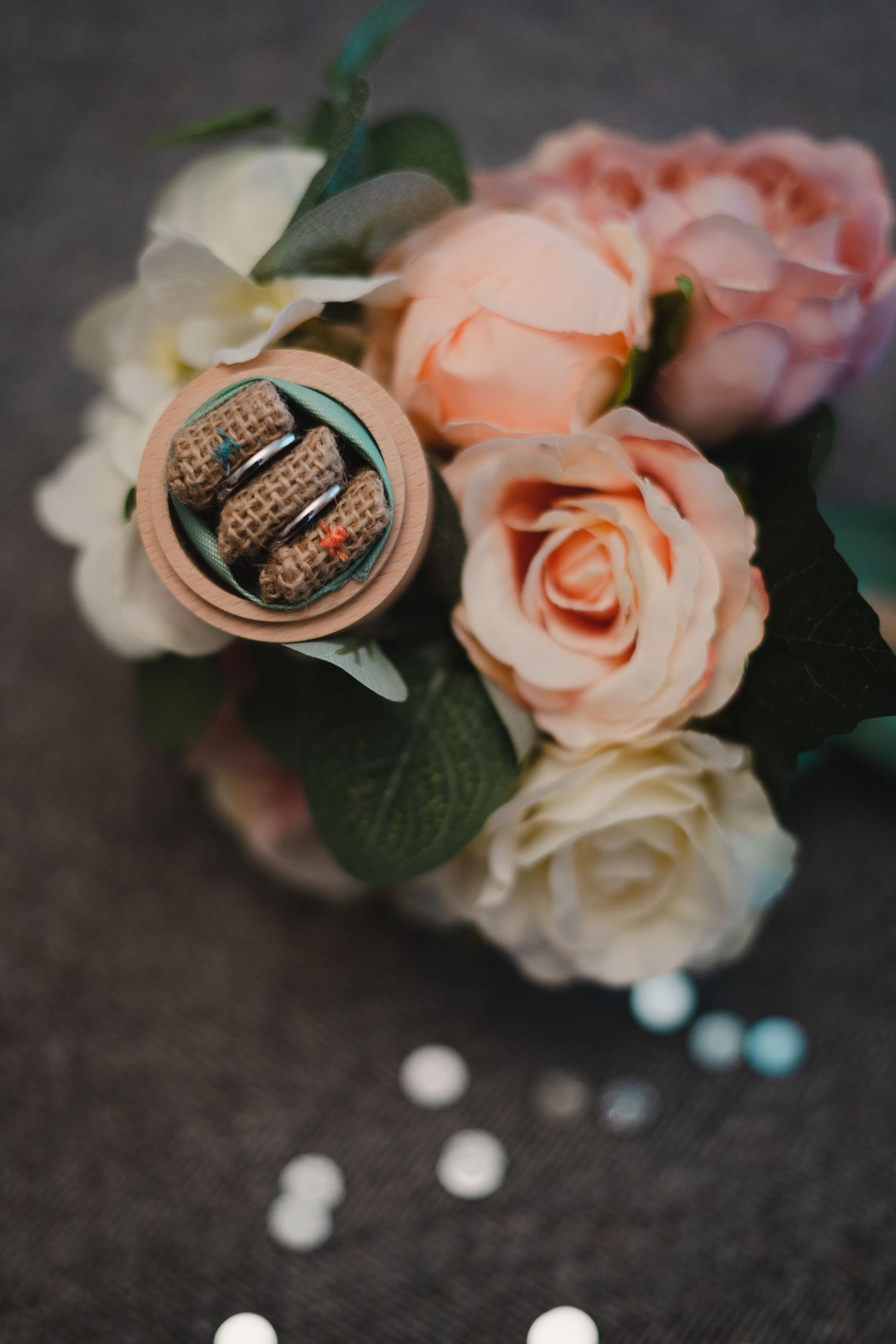 Wedding rings nestled among delicate peach roses and white pearls.