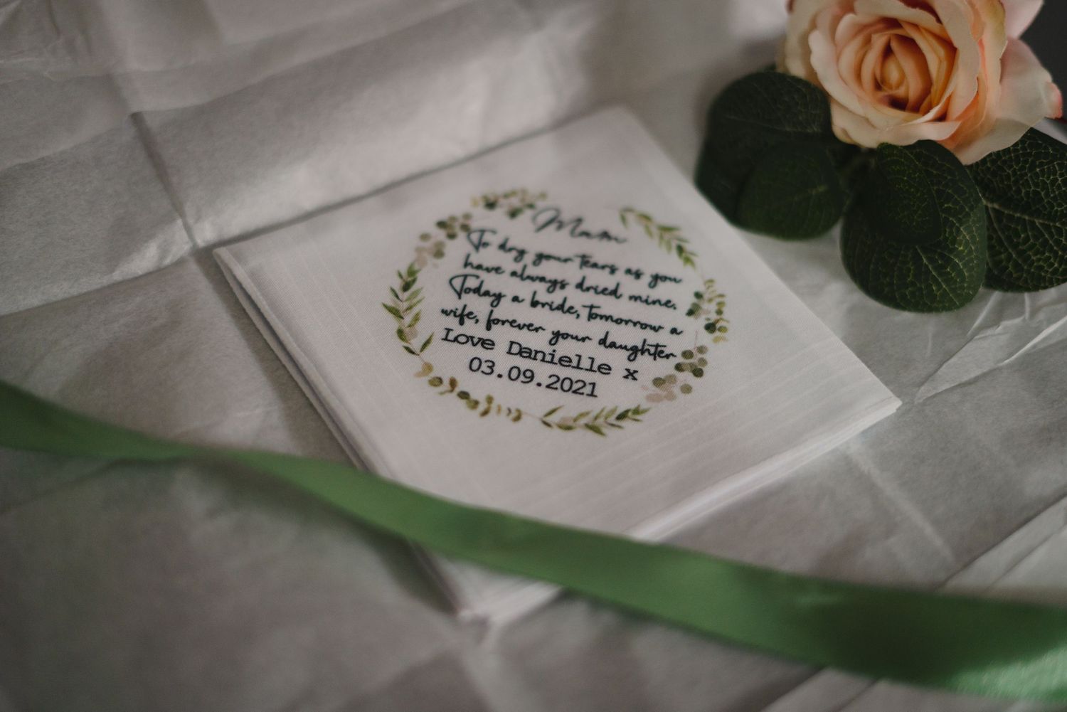 Elegant calligraphy on white wedding stationery with soft peach rose accent.