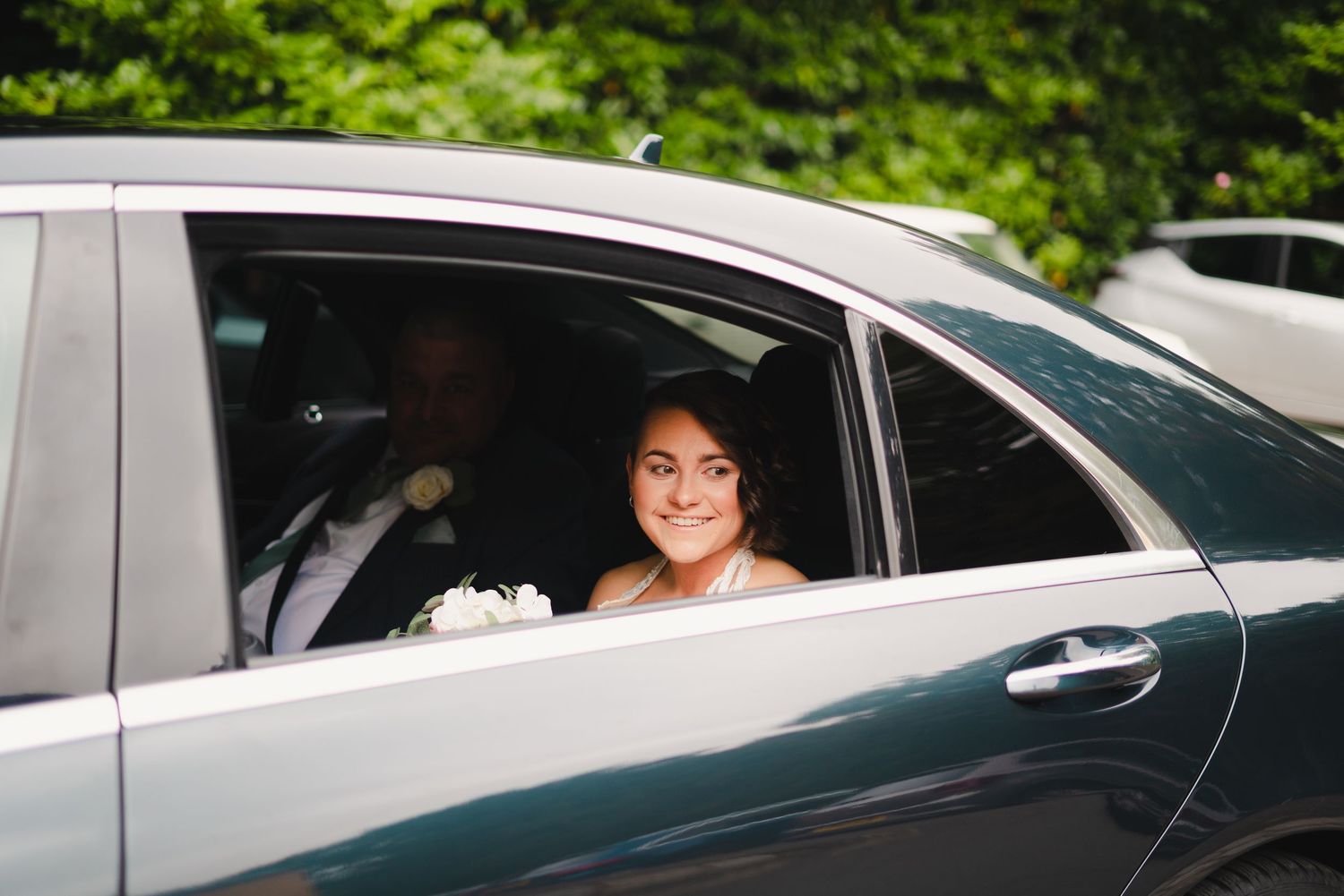 Wedding guests arriving in cars and sharing joyful moments through car windows.