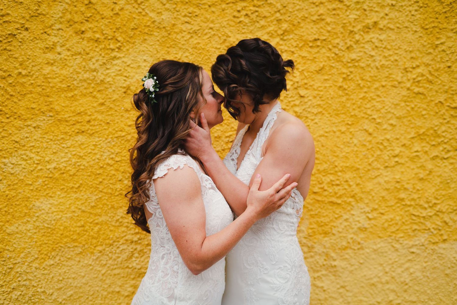 Two people embracing against a vibrant yellow wall.