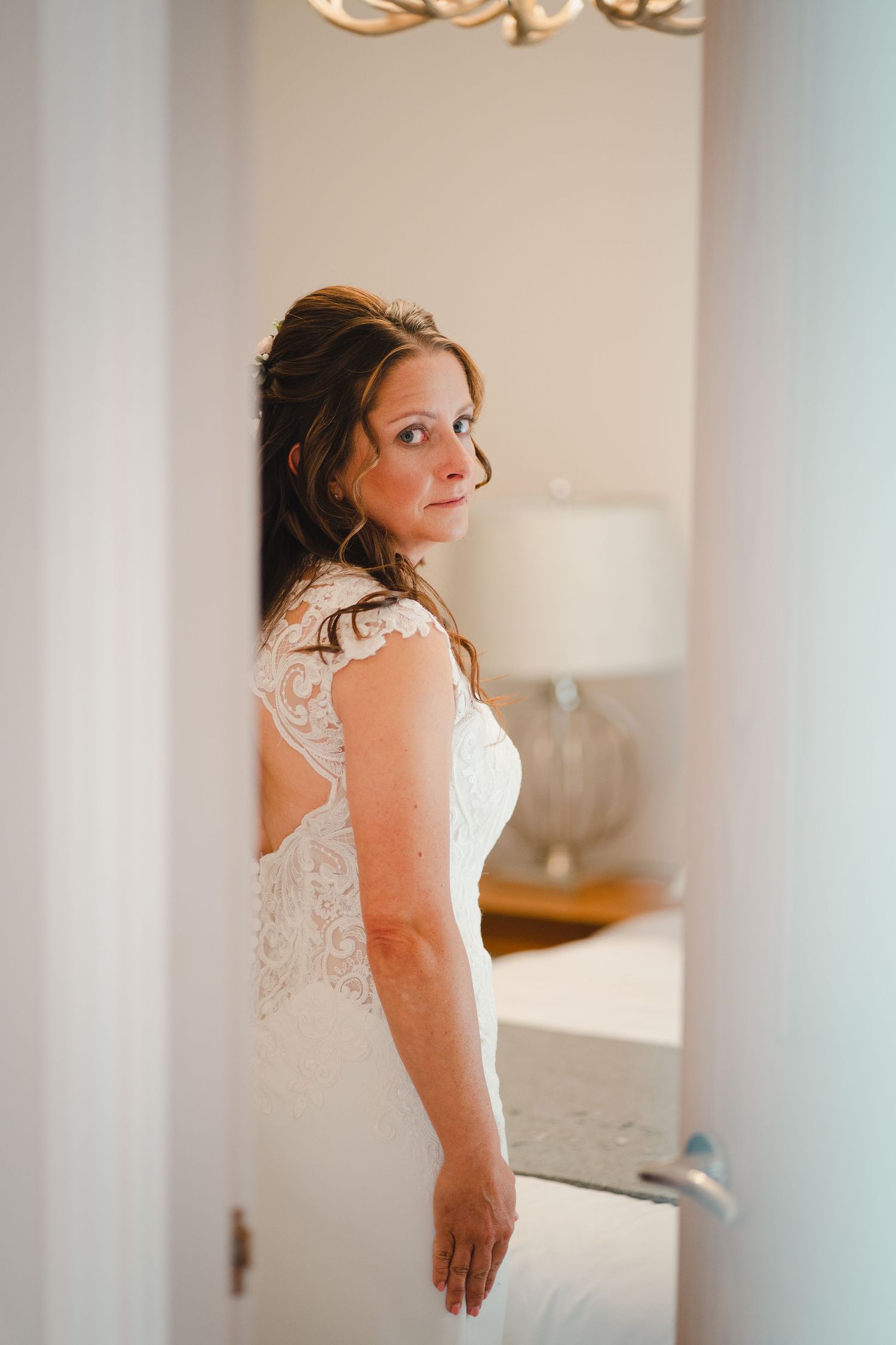 A series of detail shots showing the back of an elegant white lace wedding dress in a brightly lit room.