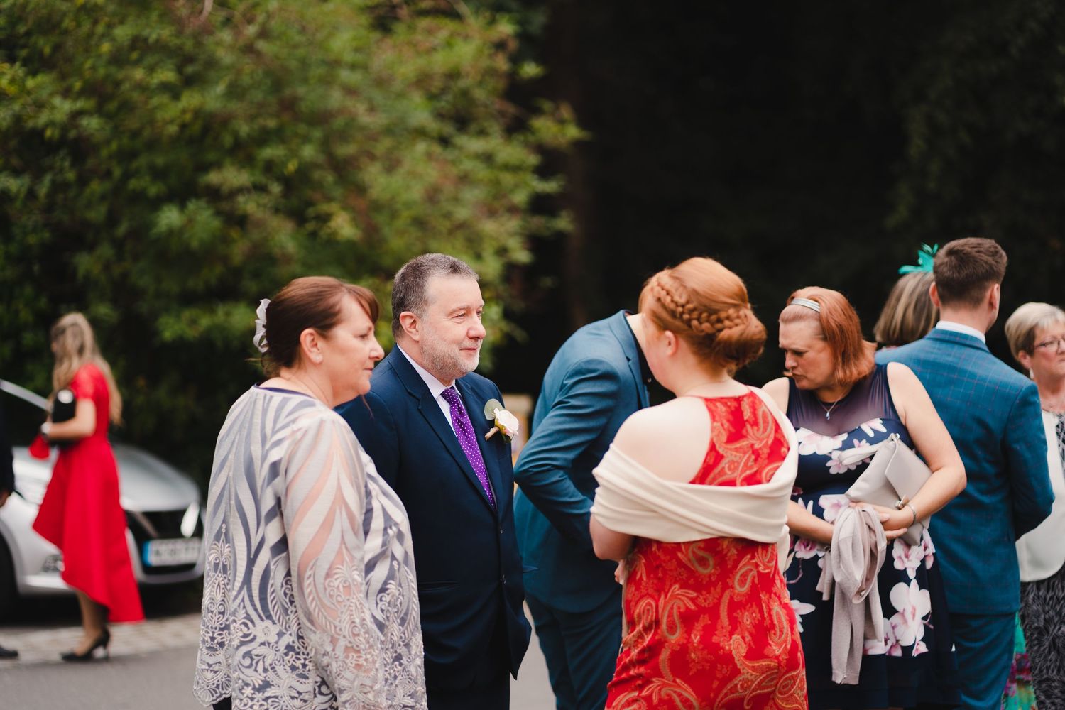 Wedding guests in formal attire mingle and dance at an outdoor reception venue.