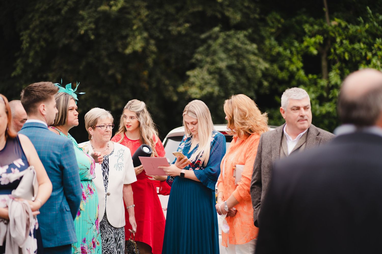 Outdoor wedding reception with guests mingling in formal attire.