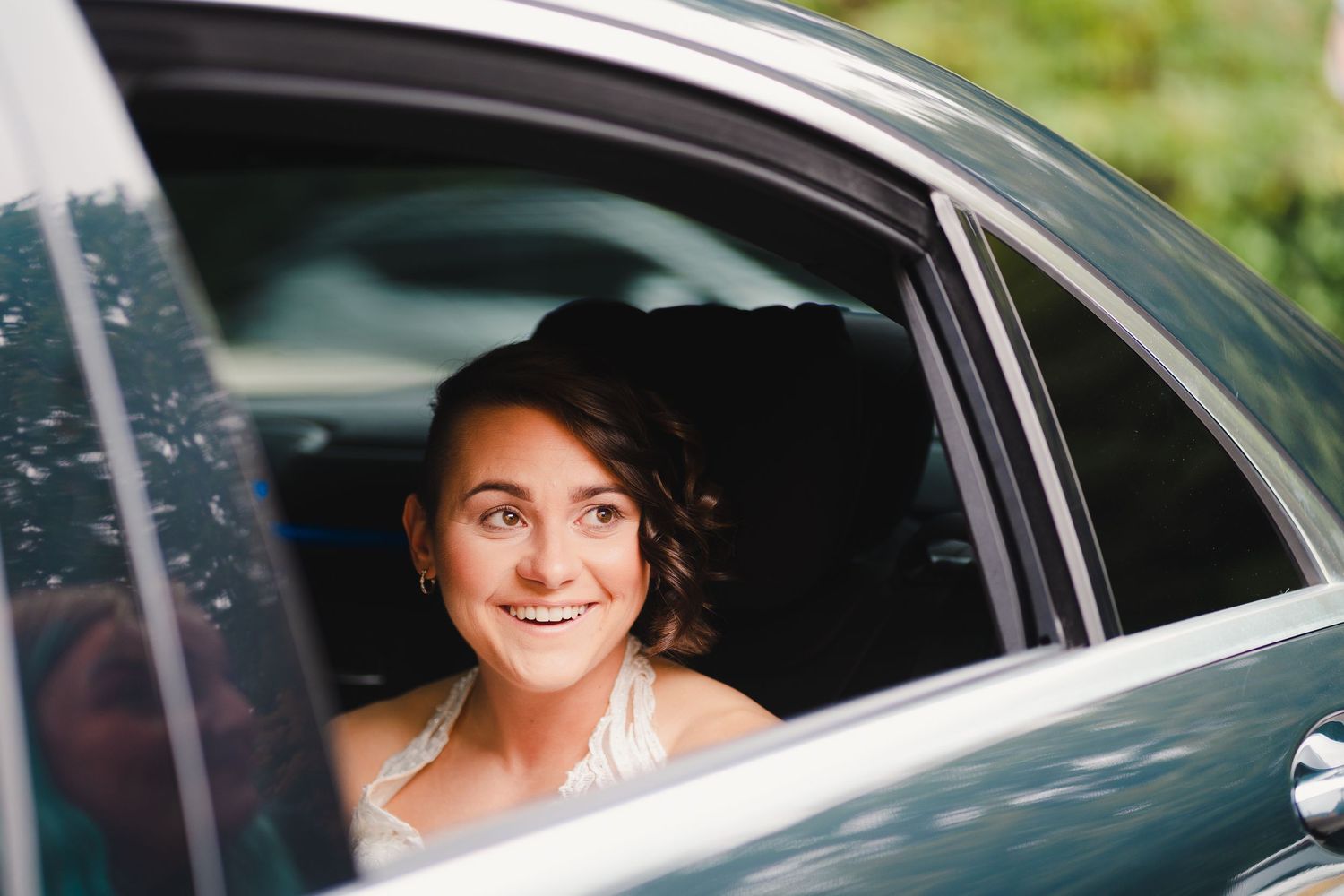 Wedding party members smiling through car windows during celebration.