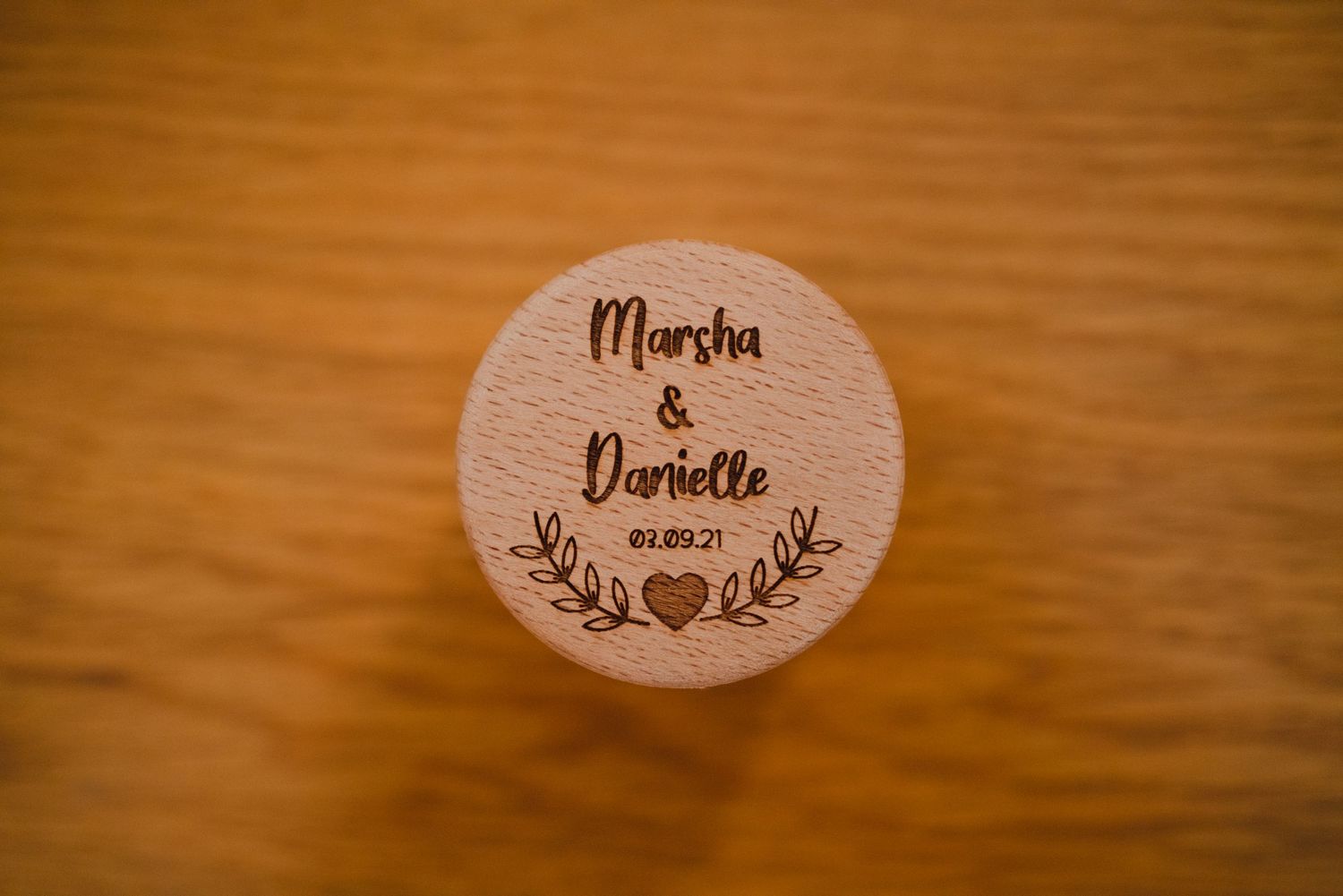 Two wooden oval name placards with decorative floral designs on a wooden surface.