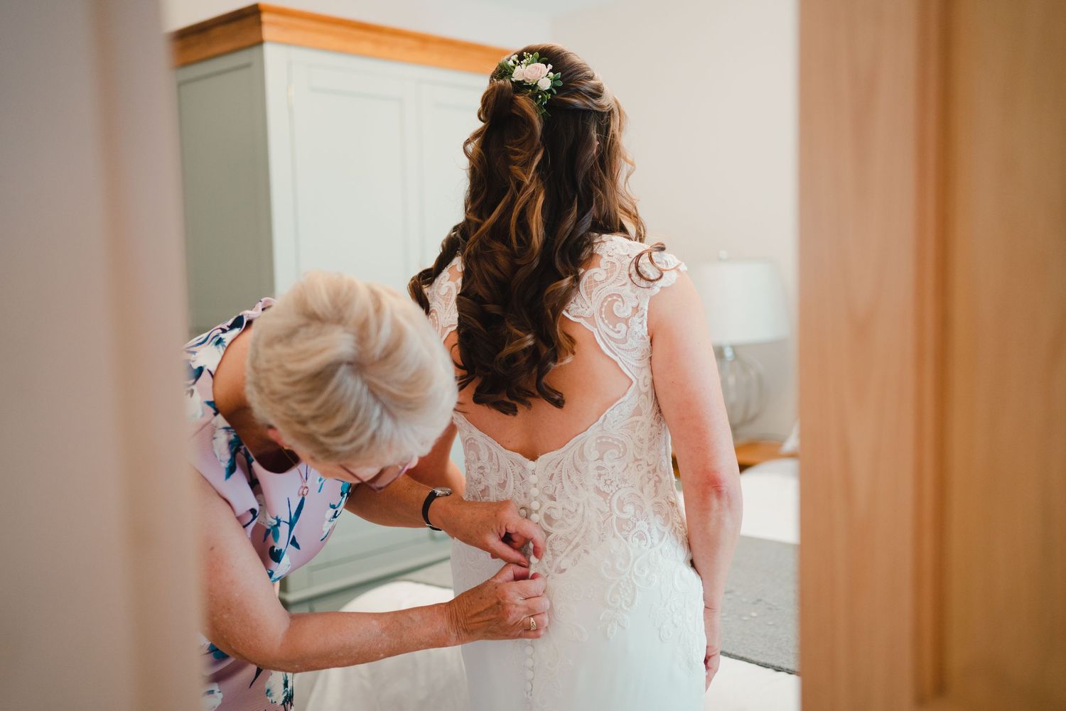 Close-up of elegant white lace wedding dress details and back buttons.