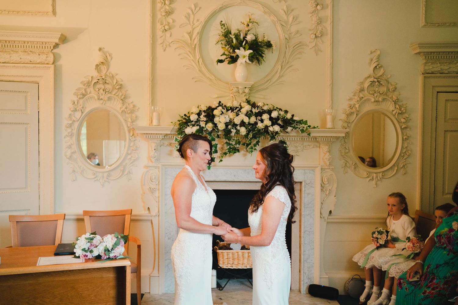Wedding ceremony moments in an elegant white room with ornate decorative details.