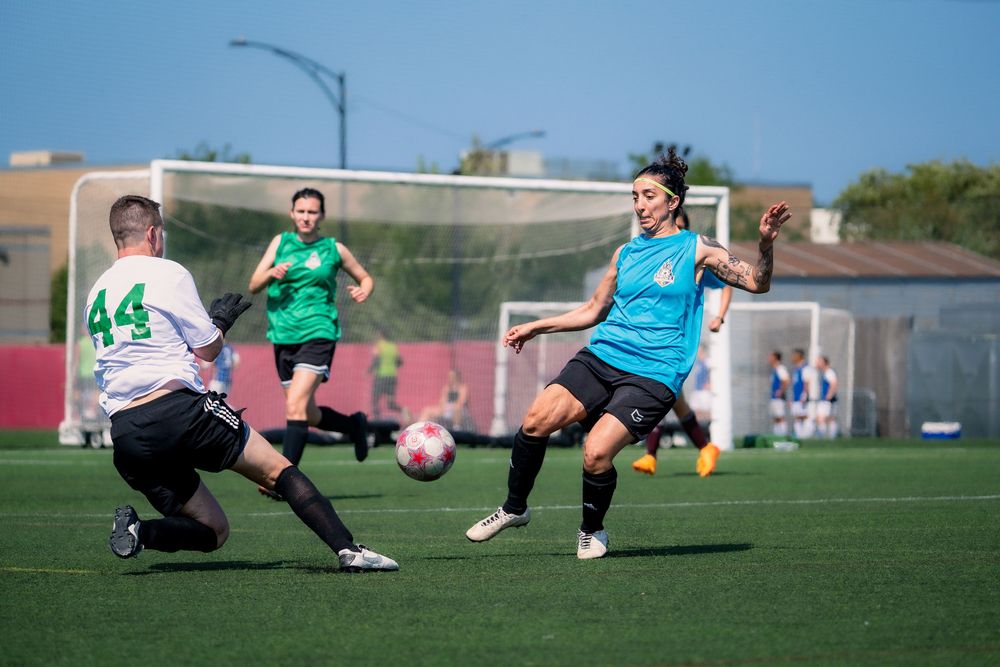 A soccer athlete attempts to score while the goalie prevents the action