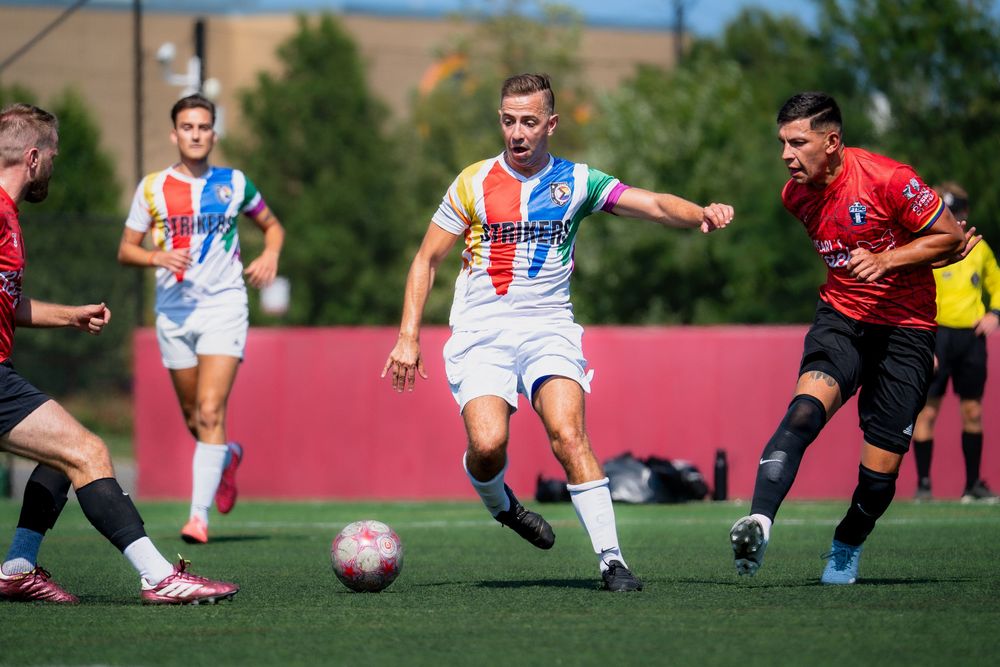 A soccer athlete attempts to maneuver the ball around opponents in red jerseys
